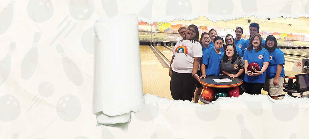 Members in matching blue shirts gathered around a table at a bowling alley, seen through a tear in a sheet of paper.
